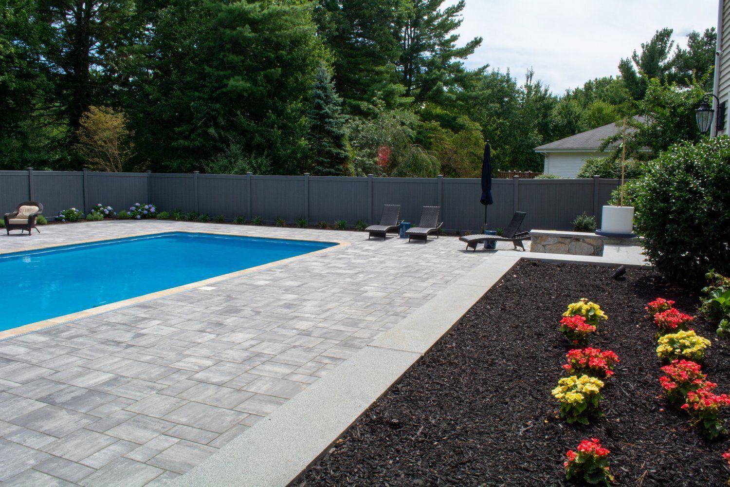 A large swimming pool is surrounded by a fence and chairs.