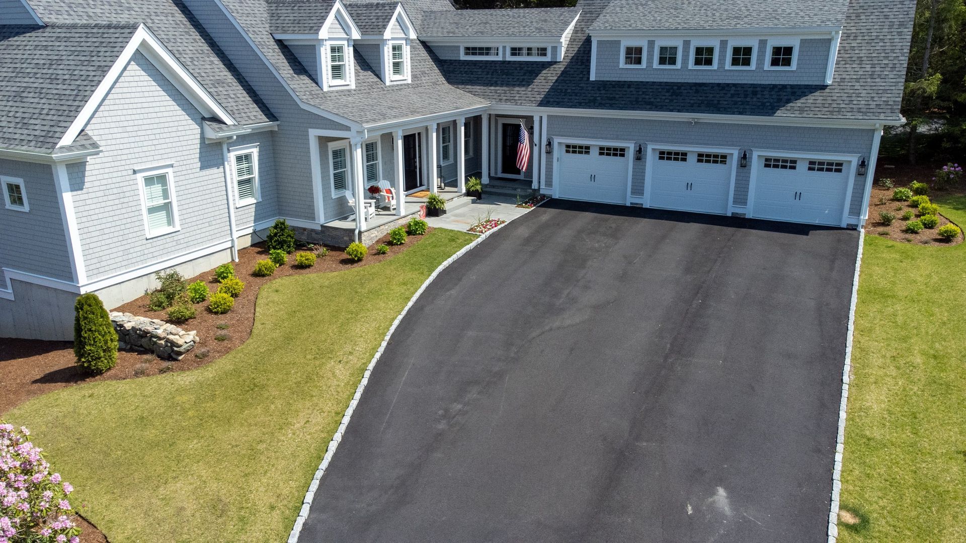 An aerial view of a large white house with a long driveway leading to it.