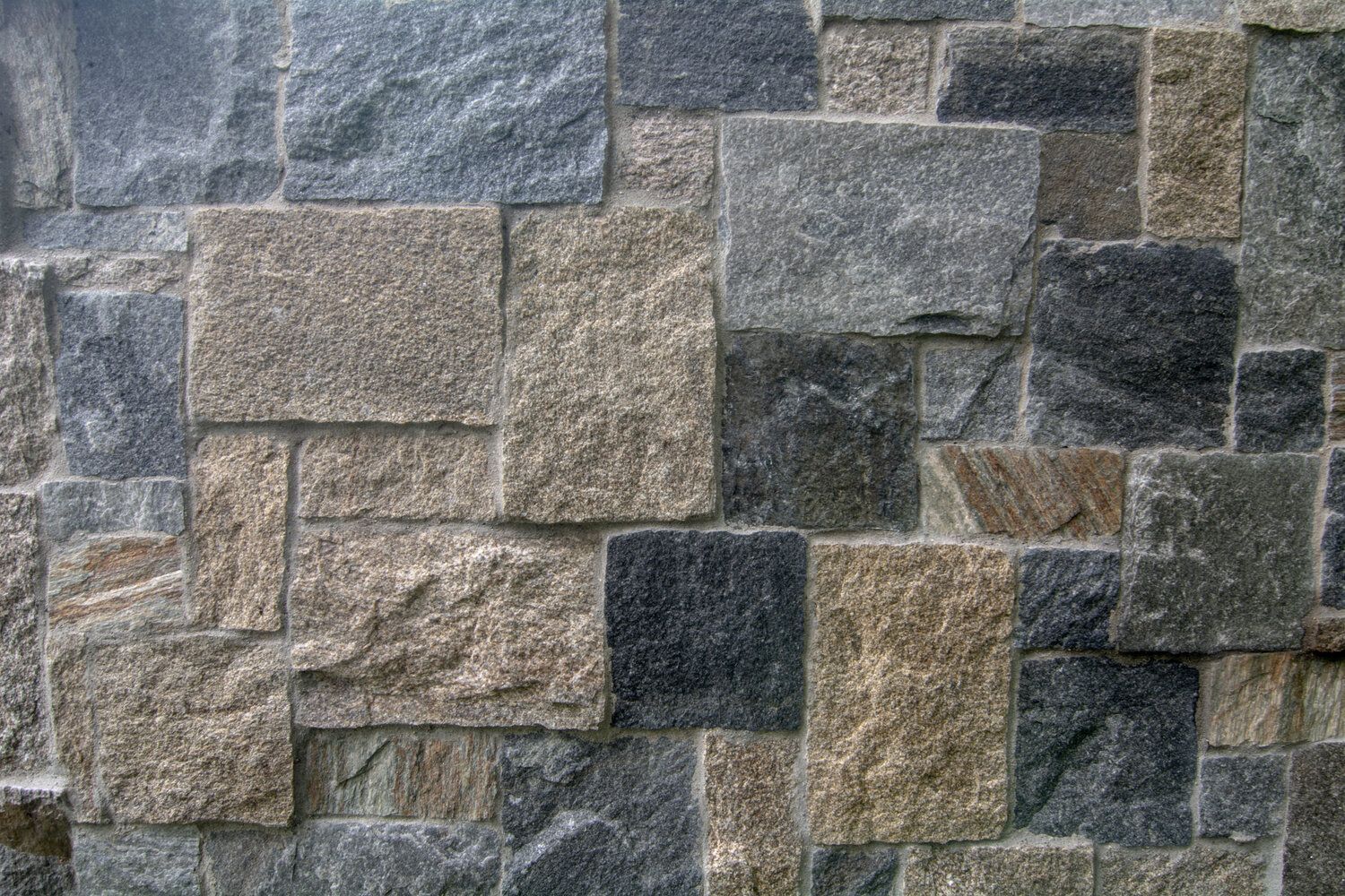 A close up of a stone wall with a brick pattern
