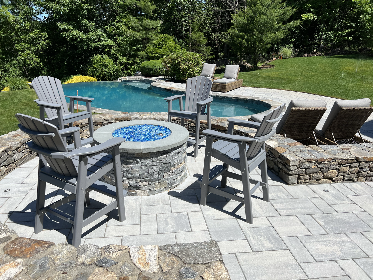 There is a fire pit in the middle of the patio with chairs around it.