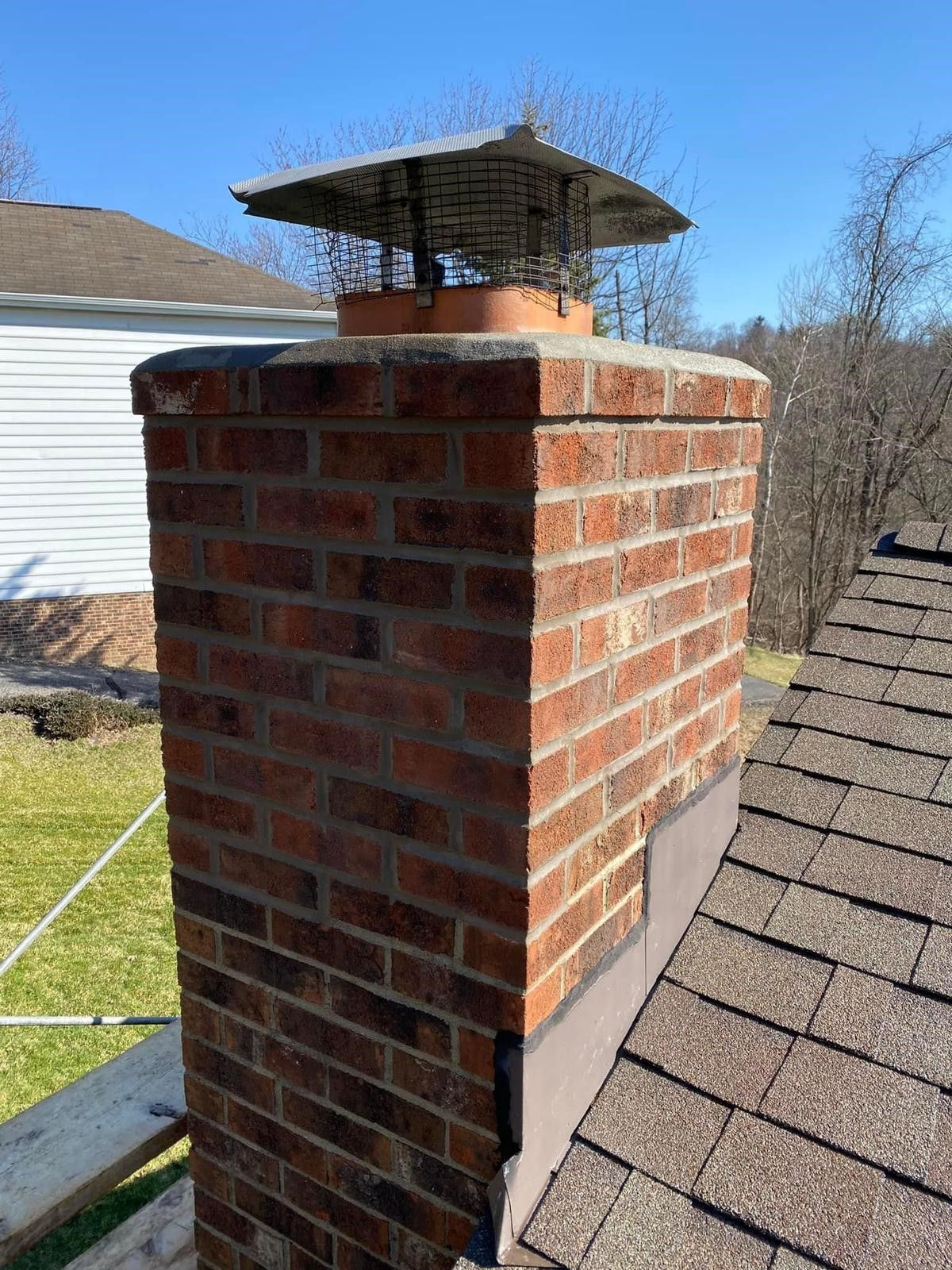A brick chimney is sitting on top of a roof