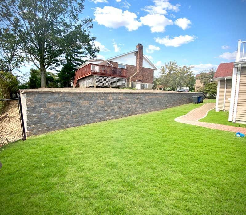 A backyard with a brick wall and a house in the background