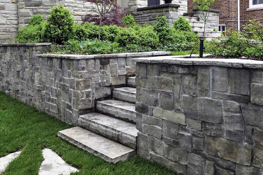 A stone wall with stairs leading up to a house