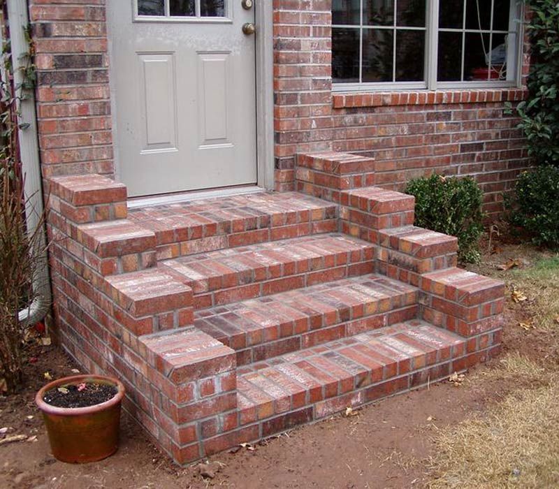 A brick porch with stairs and a potted plant in front of it