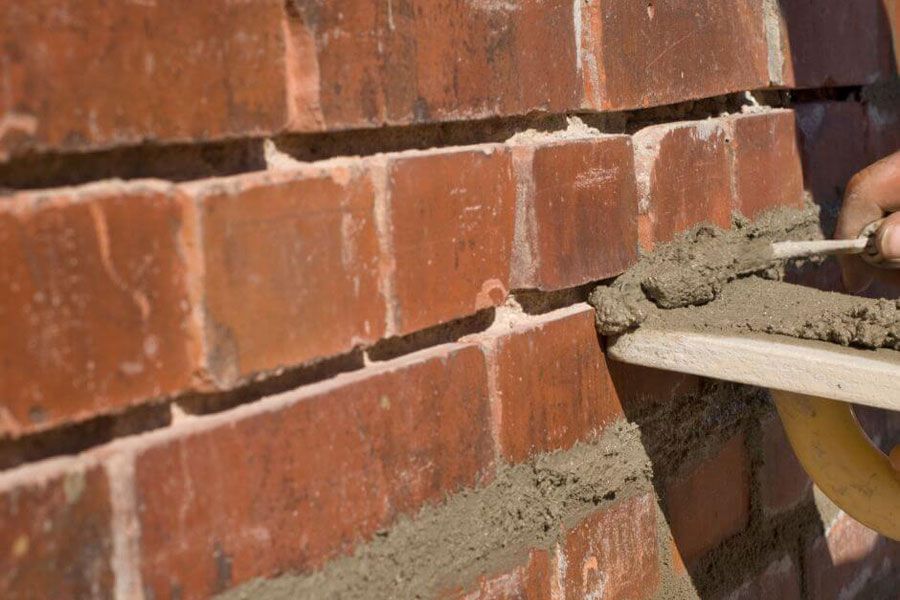 A person is laying concrete on a brick wall with a trowel
