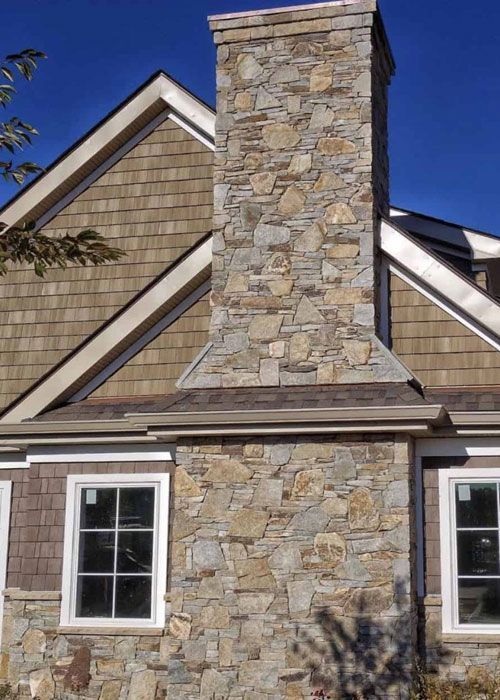 A large stone chimney is on the side of a house