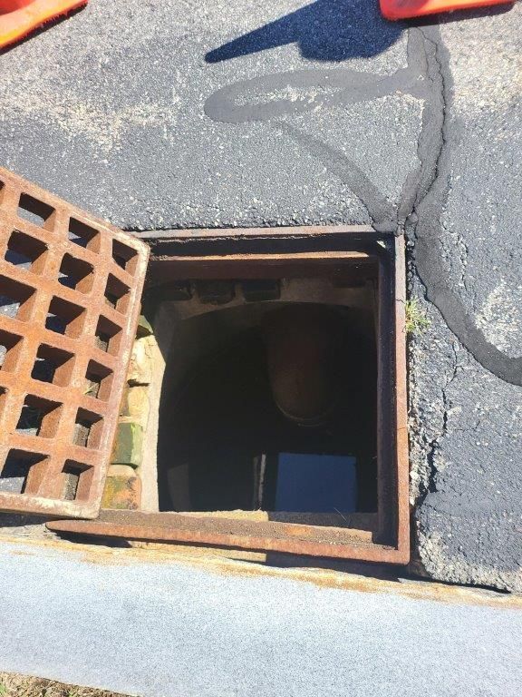 A manhole cover is open on the side of the road.