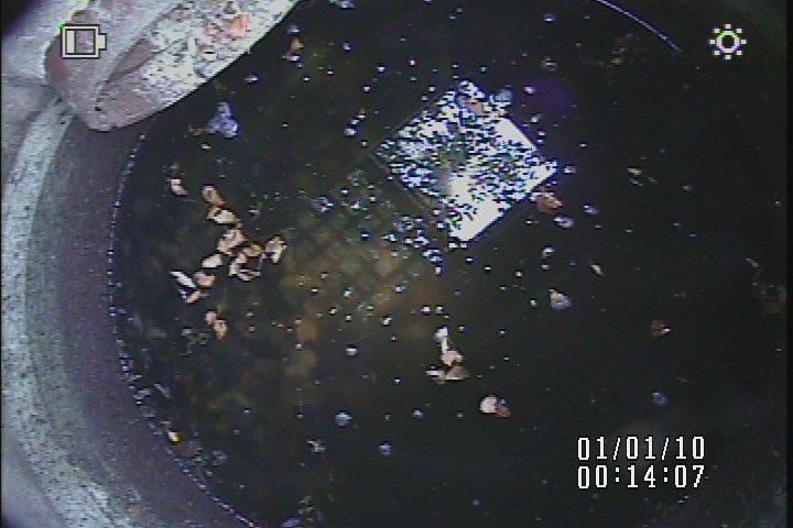 A camera is taking a picture of a hole in the ground filled with water.