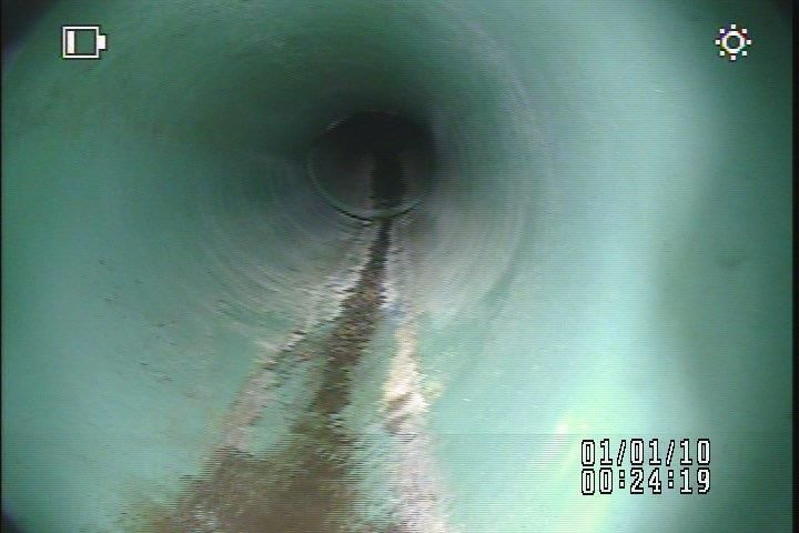 A close up of a green pipe with water coming out of it.
