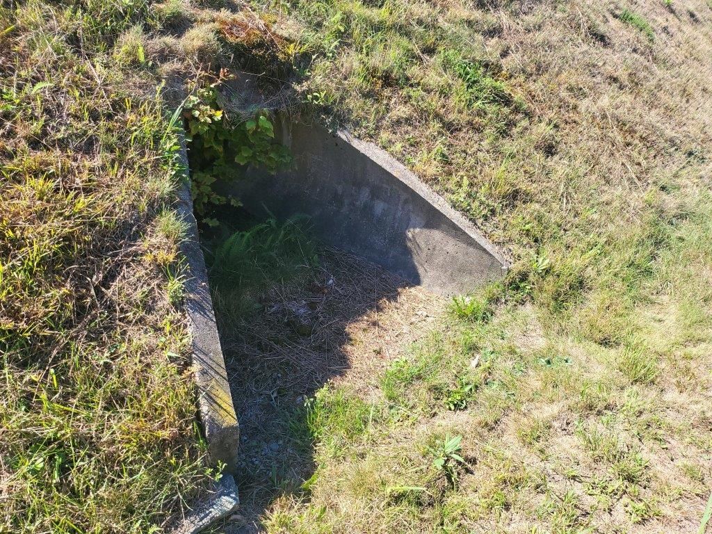 A concrete structure is sitting in the middle of a grassy field.