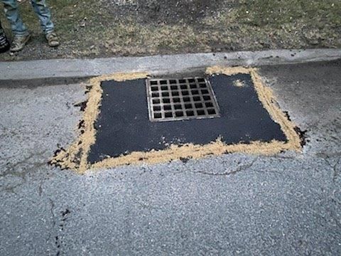 A manhole cover is being repaired on the side of the road.