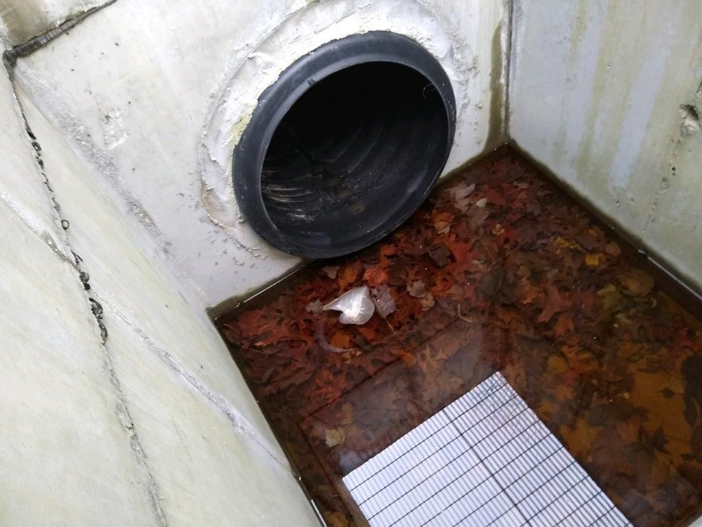 A black pipe is coming out of a hole in a wall.