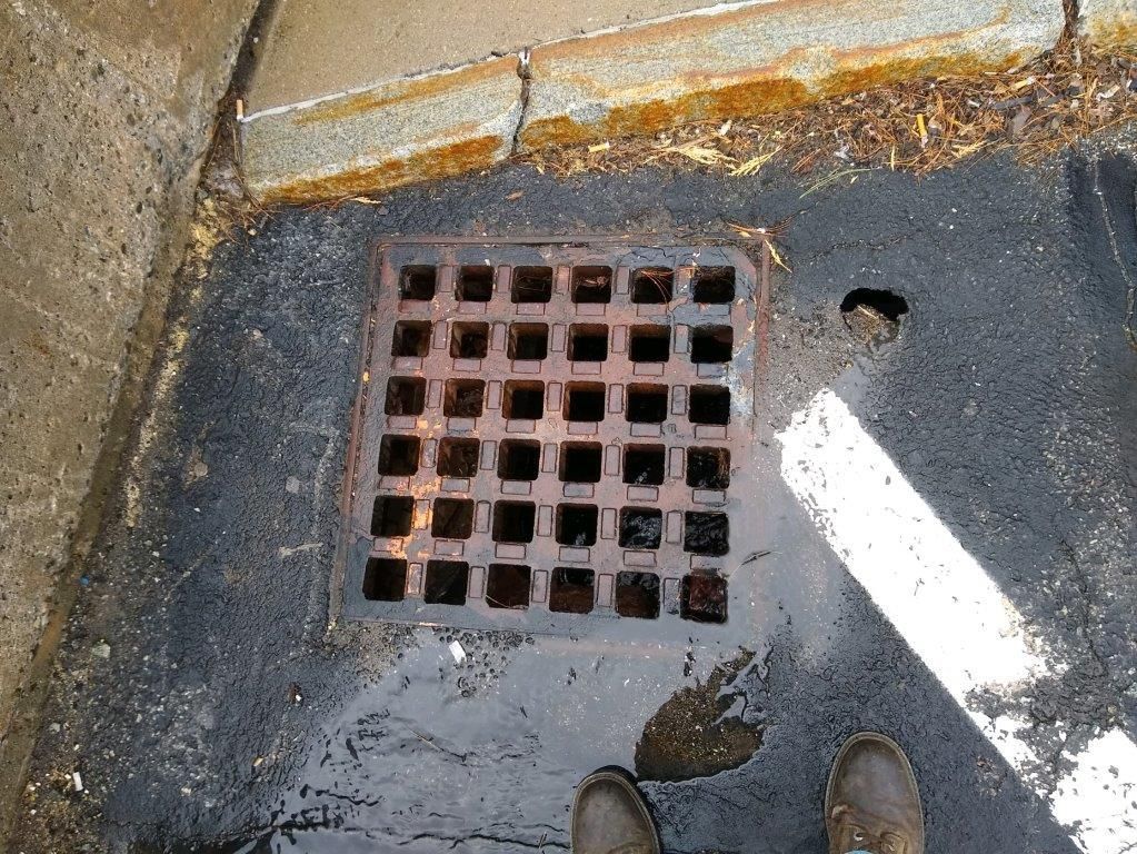 A manhole cover on the ground with a hole in it.