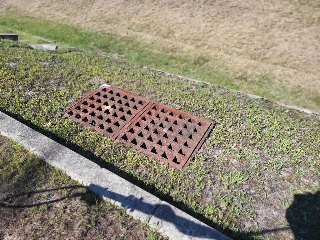 A rusty manhole cover is sitting on the side of a road.