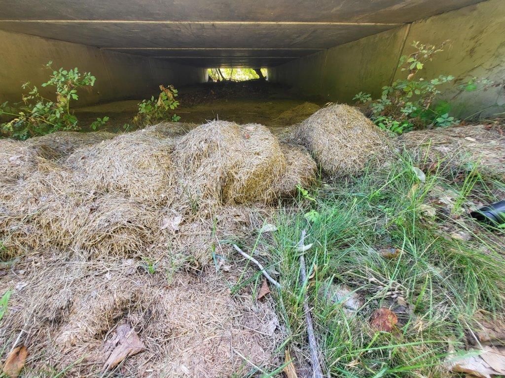 A pile of dirt and grass under a bridge.