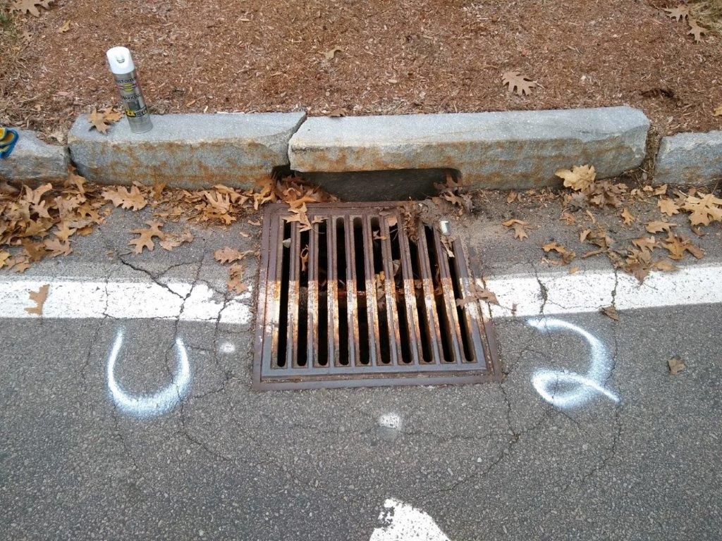 A manhole cover is sitting on the side of the road next to a curb.