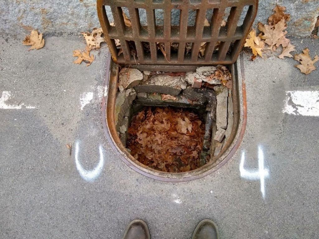 A manhole cover on the side of a road with a hole in it.