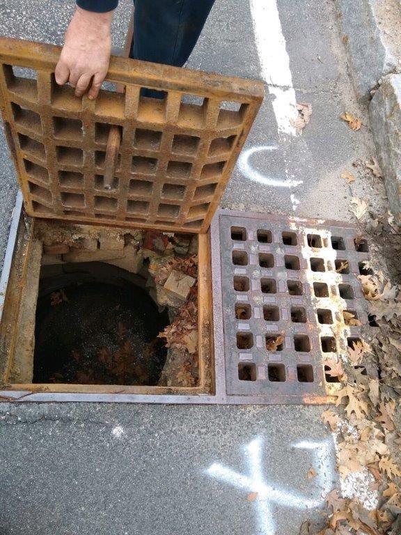 A manhole cover is open on the side of the road.