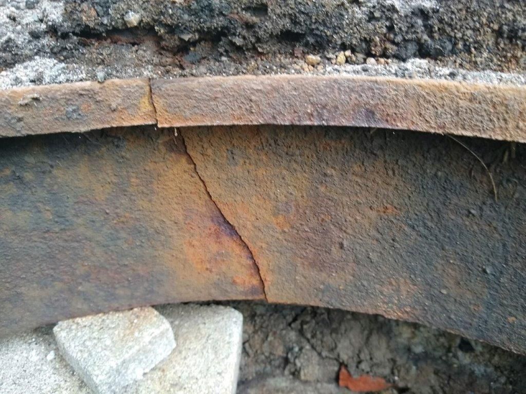 A rusty piece of metal is sitting on the ground.