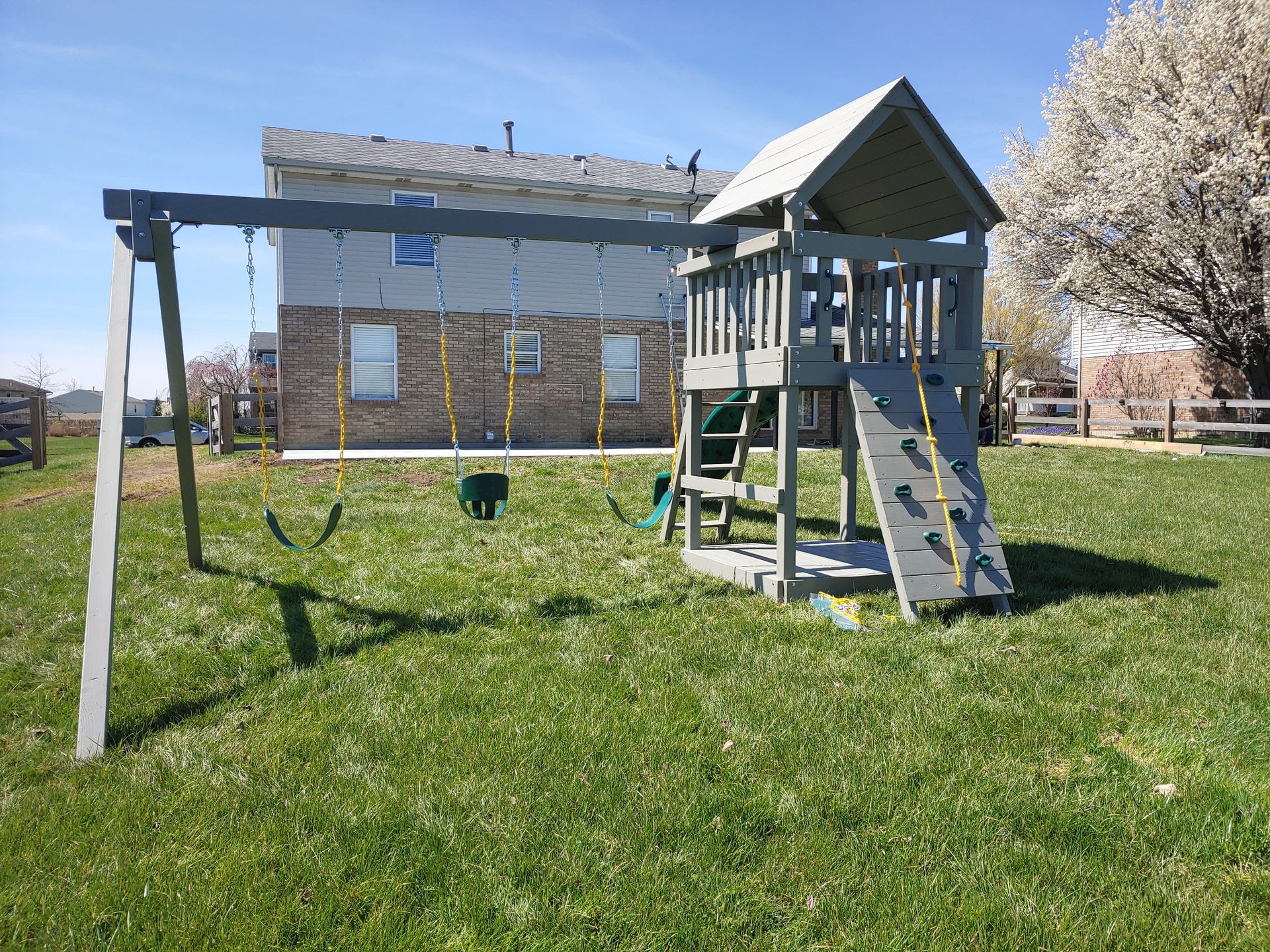 Playground with brown wooden structure, rock wall, rope, slide, and picnic table.