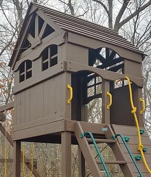 Brown wooden playhouse with a ladder, climbing rope, and yellow handles.