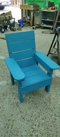Blue wooden Adirondack chair in a workshop setting.