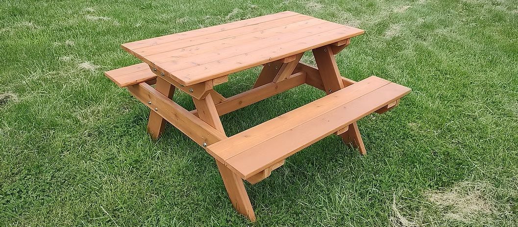 Wooden picnic table on a green grassy lawn.