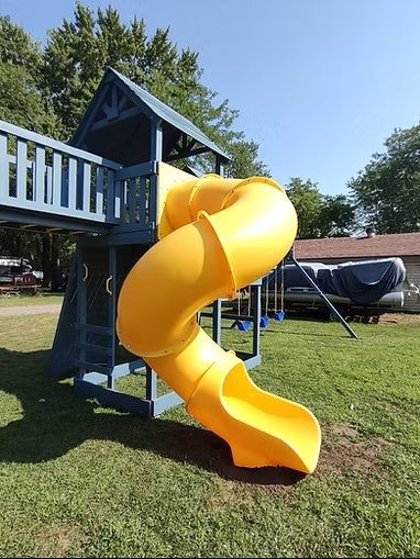 Yellow spiral slide attached to a blue wooden playset in a grassy yard.