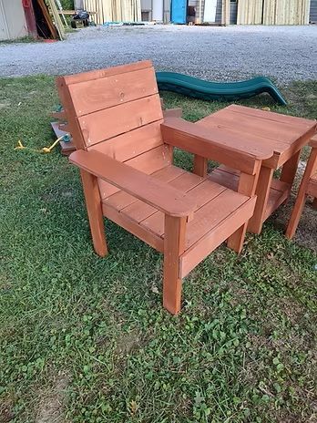 Wooden chair with attached side table on grass. Chair and table are orange-brown.