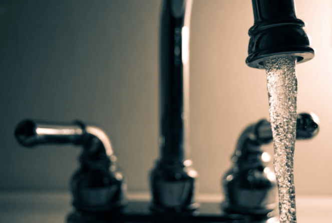 Close-up of a modern chrome bathroom faucet with water flowing from the spout.