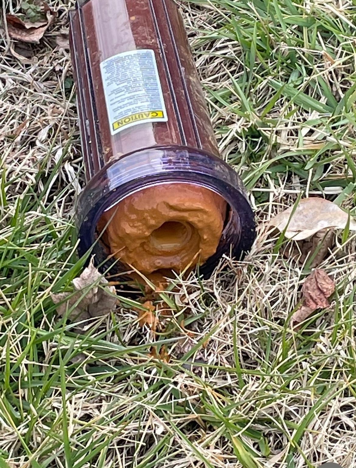 Brown rolled mat with label lying on grass, showing an orange foam end inside