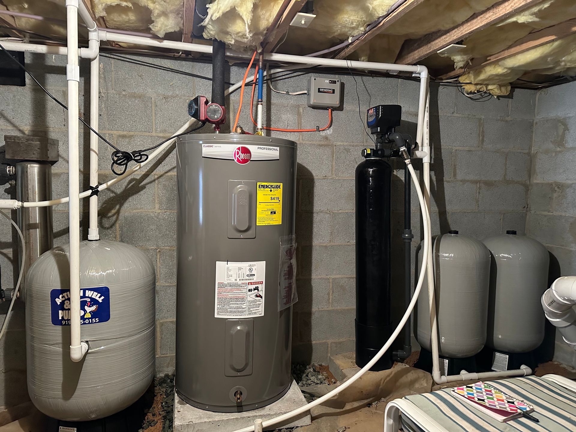 Basement utility room with water heater, pressure tanks, and plumbing equipment around a furnace.