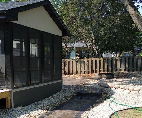A brick walkway leads to a screened in porch