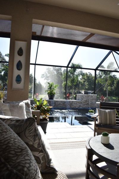 Sunlit living space with view of pool and foliage; plush seating.