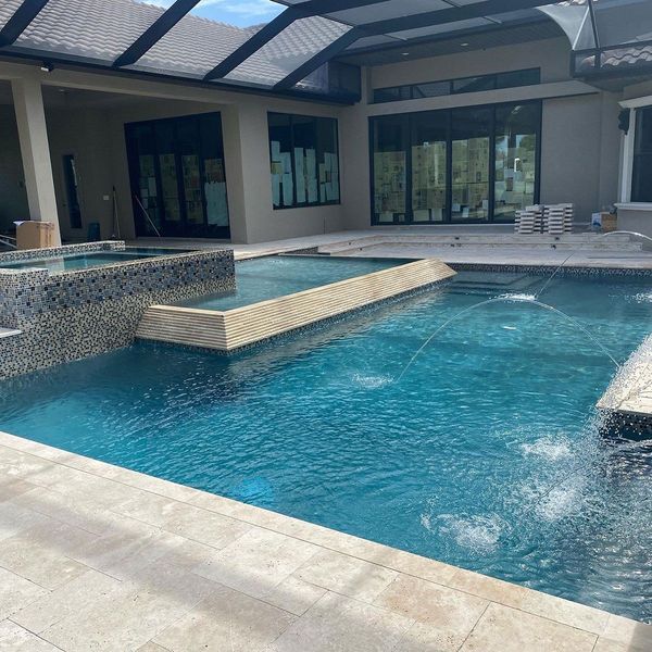 Luxury backyard pool with fountains, hot tub, and modern architecture.