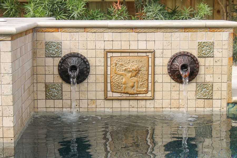 Water fountain with two spout heads and a central relief, tiled wall.