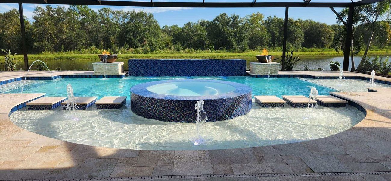 A luxurious backyard swimming pool with a hot tub and water features, set against a backdrop of trees.