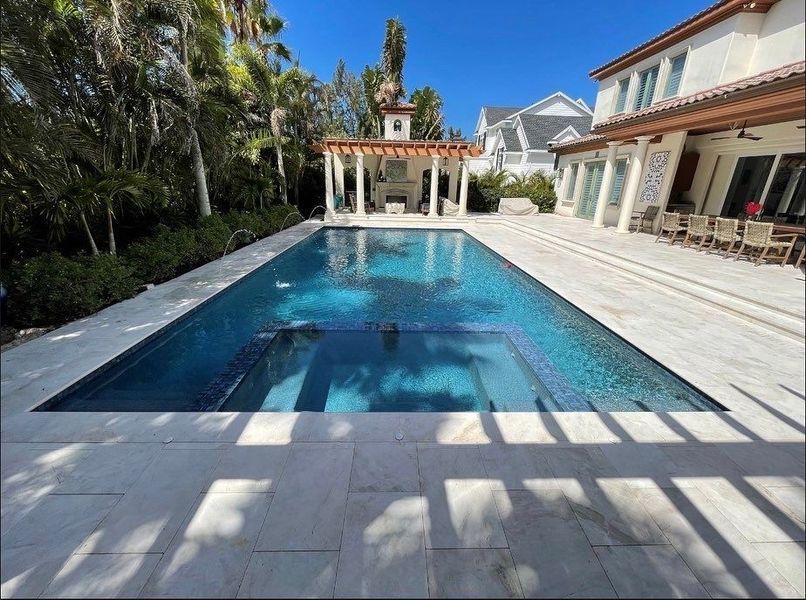 Pool and spa with blue water and surrounding patio at a house.
