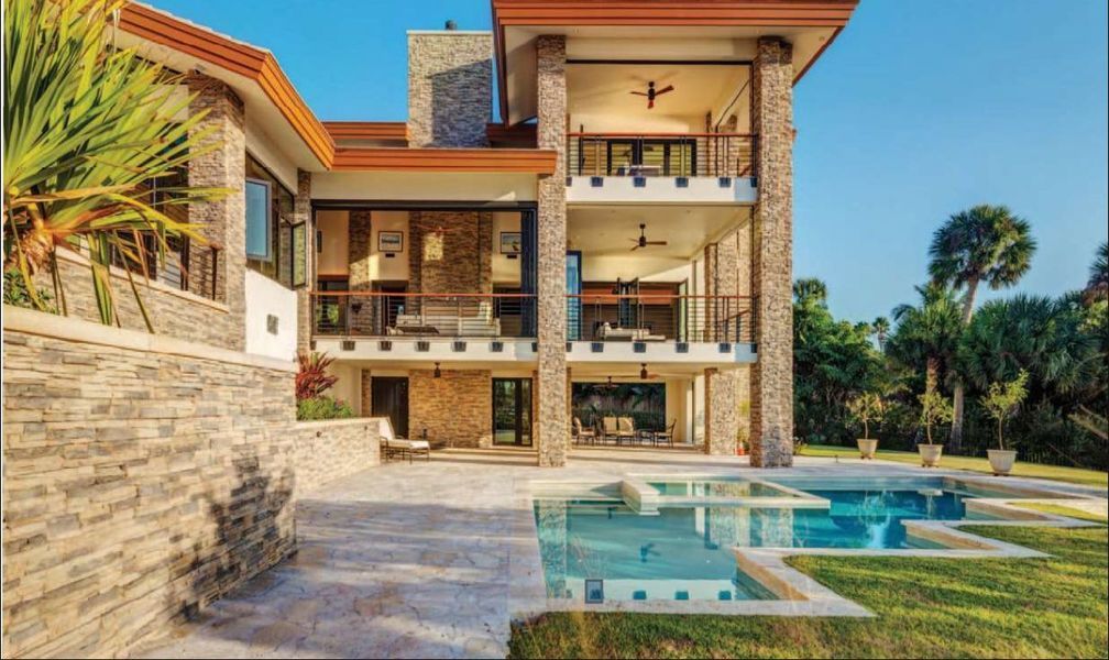 Luxurious multi-story home with a pool, balcony, and stone accents.