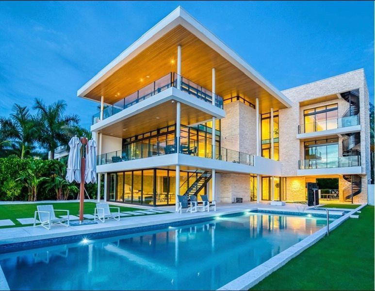 Modern multi-story house with a pool. Features glass walls, balconies, and evening lighting.