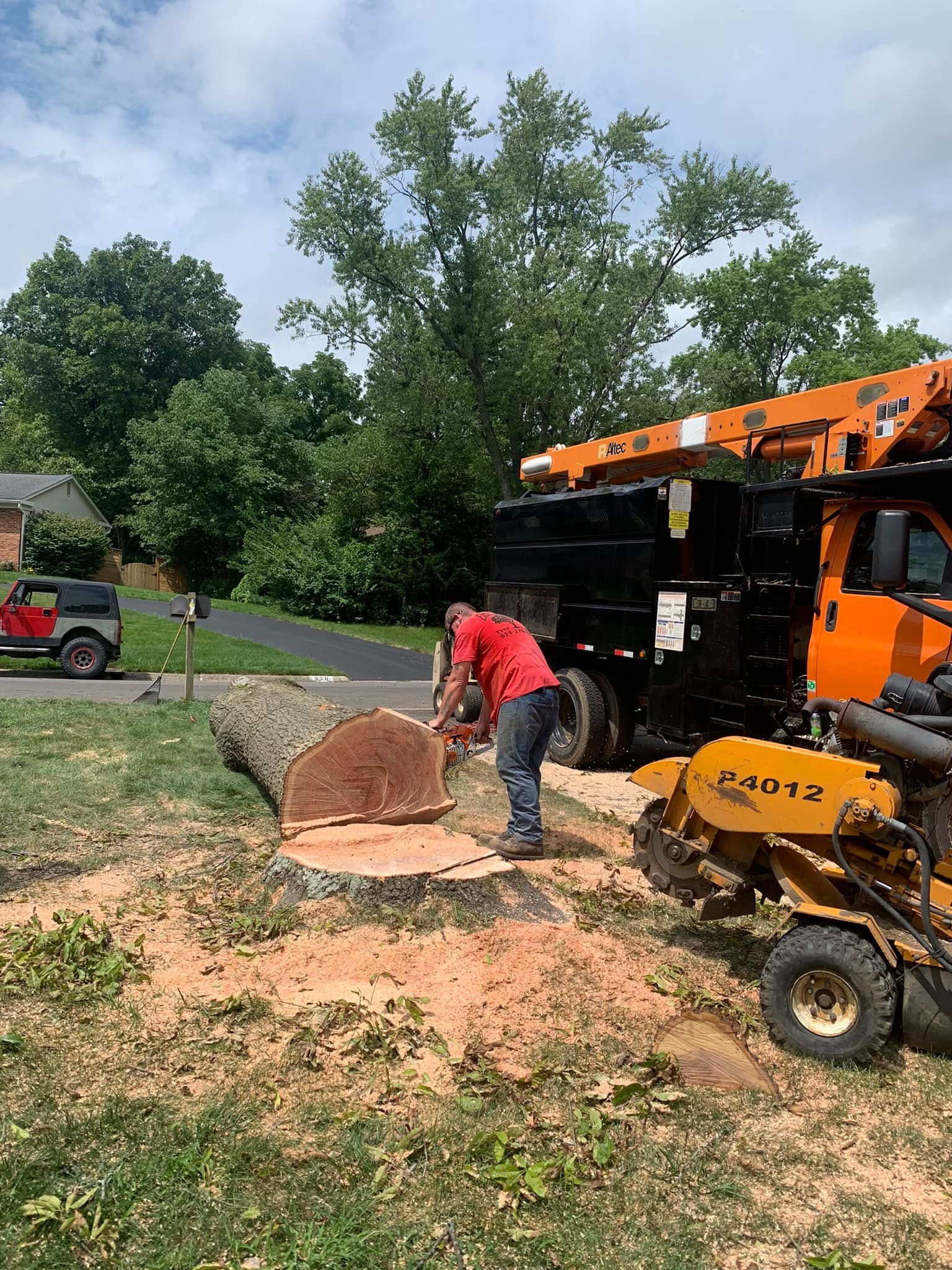A man is cutting a tree stump with a chainsaw.