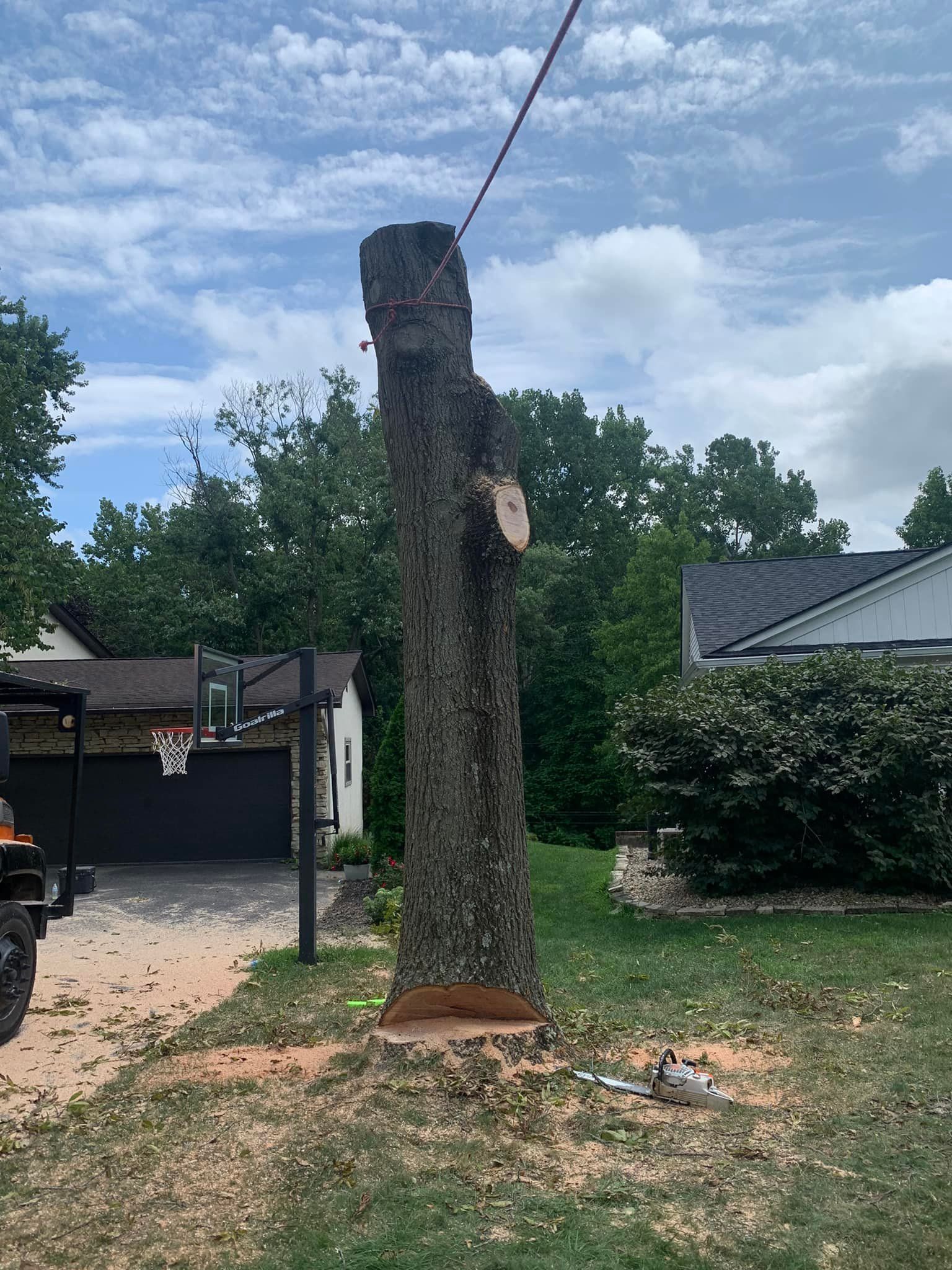 A large tree stump is sitting in front of a house.