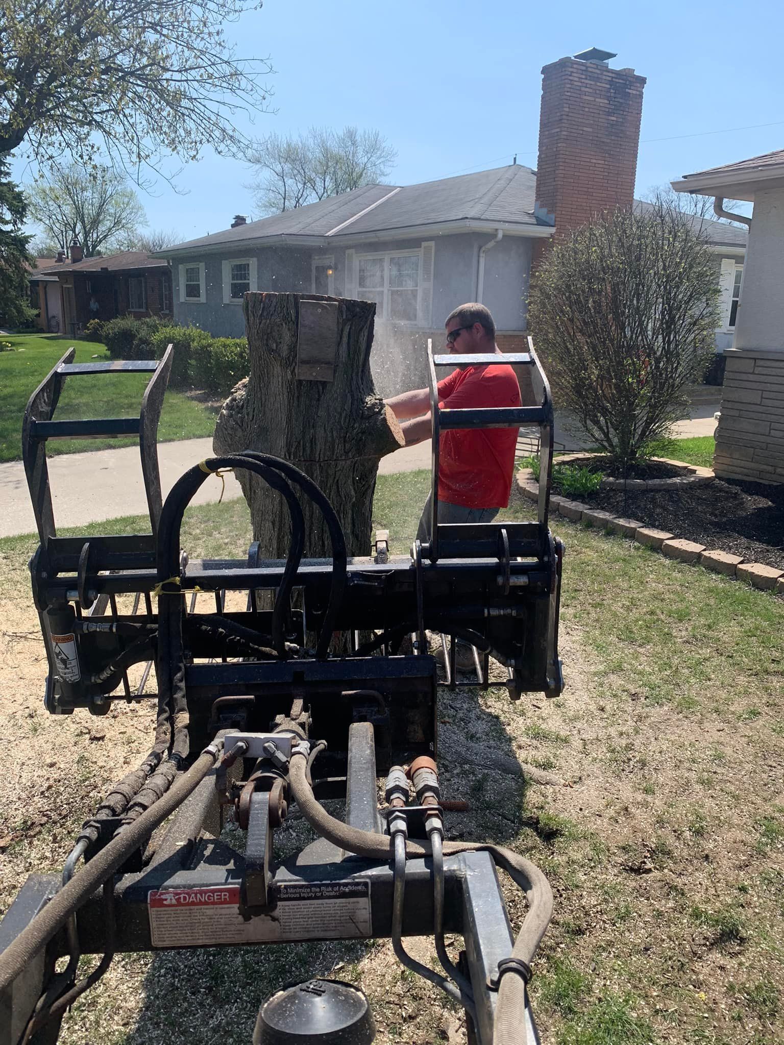 A man is using a machine to remove a tree stump.