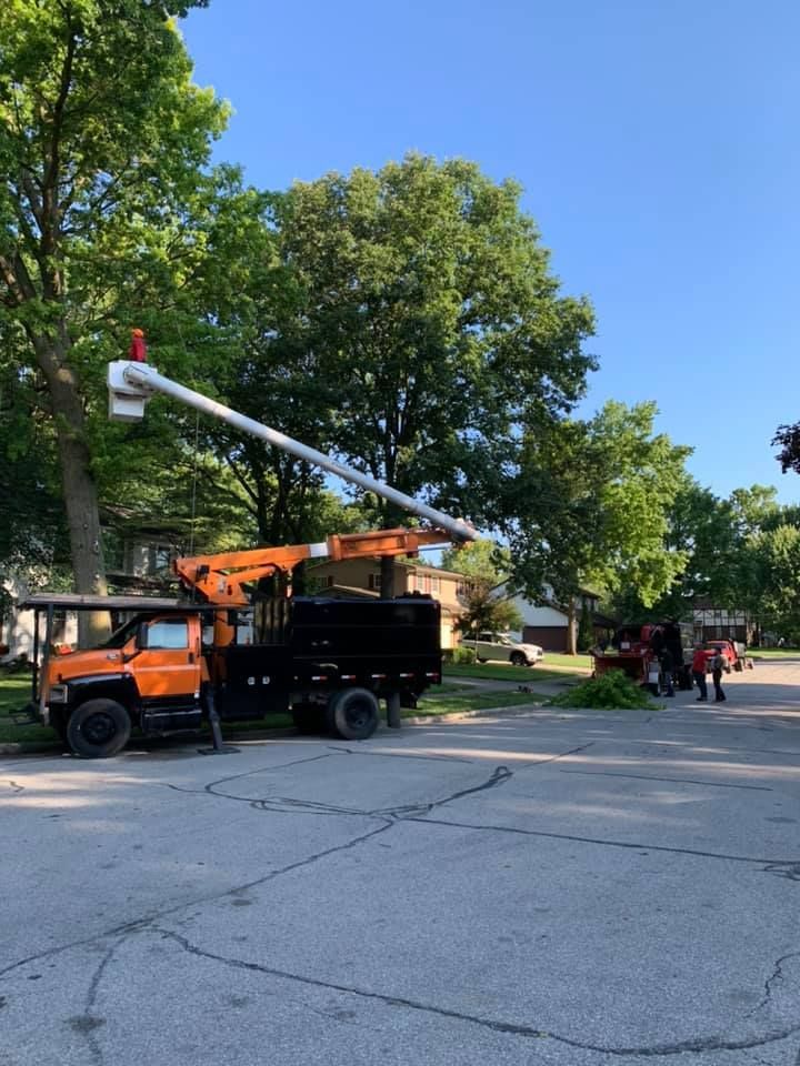 An orange truck with a crane on top of it is parked on the side of the road.