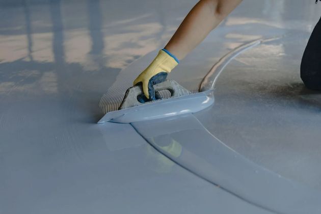 Gloved hand smoothing clear film over a glossy light-blue surface