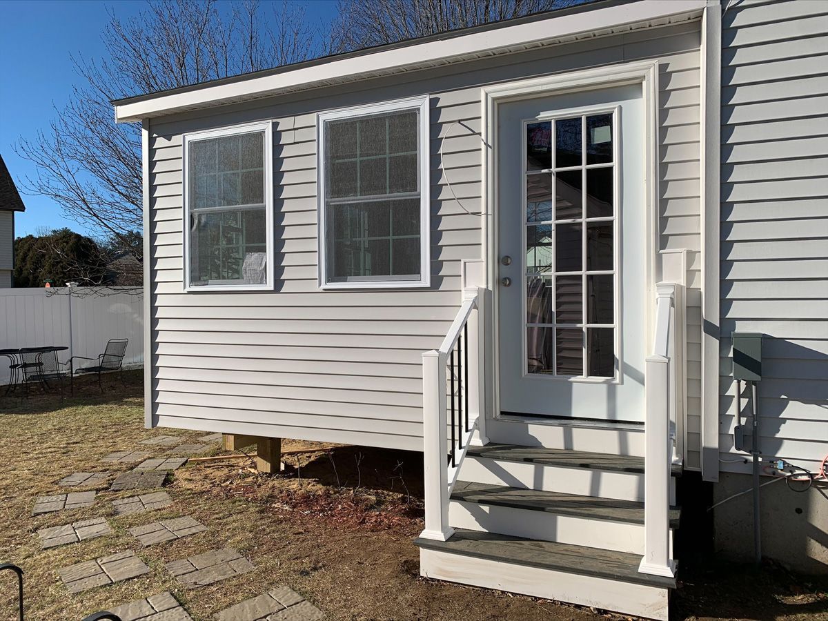 A white house with a porch and stairs leading to it.