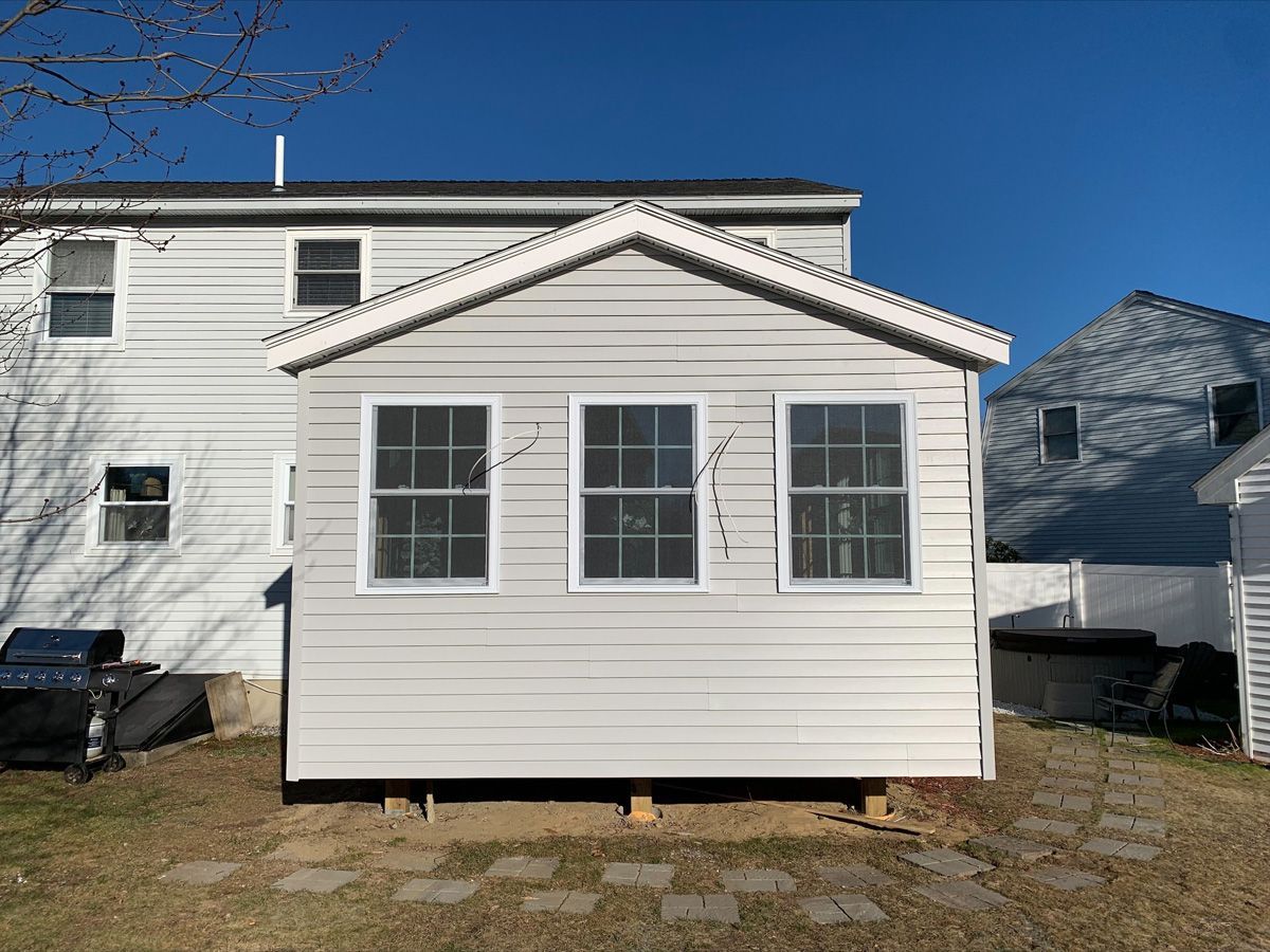 A white shed is sitting in the backyard of a house.