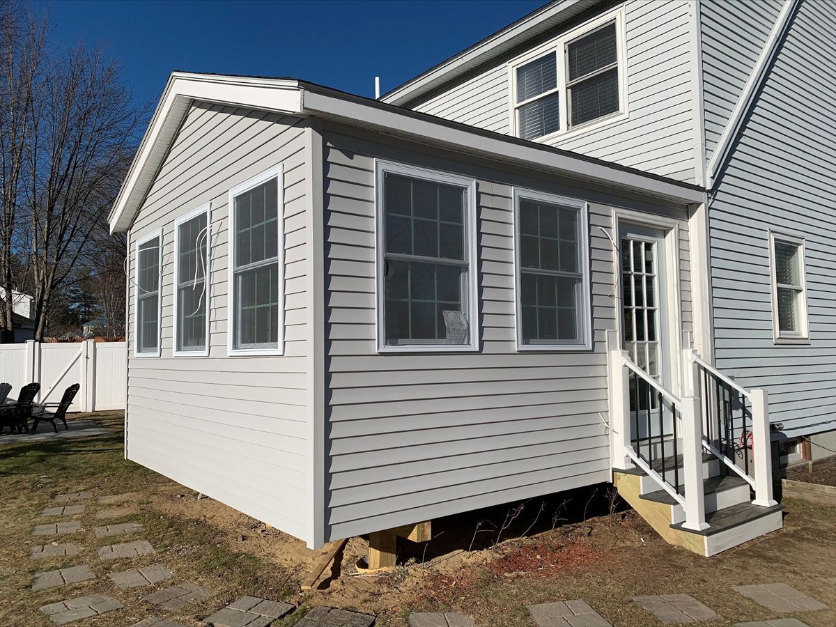 A white house with a sunroom attached to it.