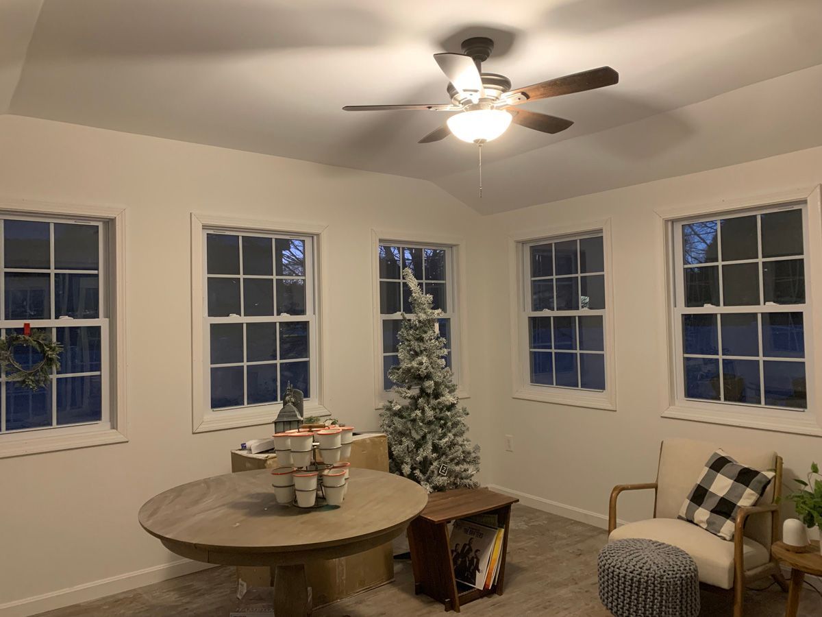 A living room with a table , chairs , a ceiling fan and a christmas tree.