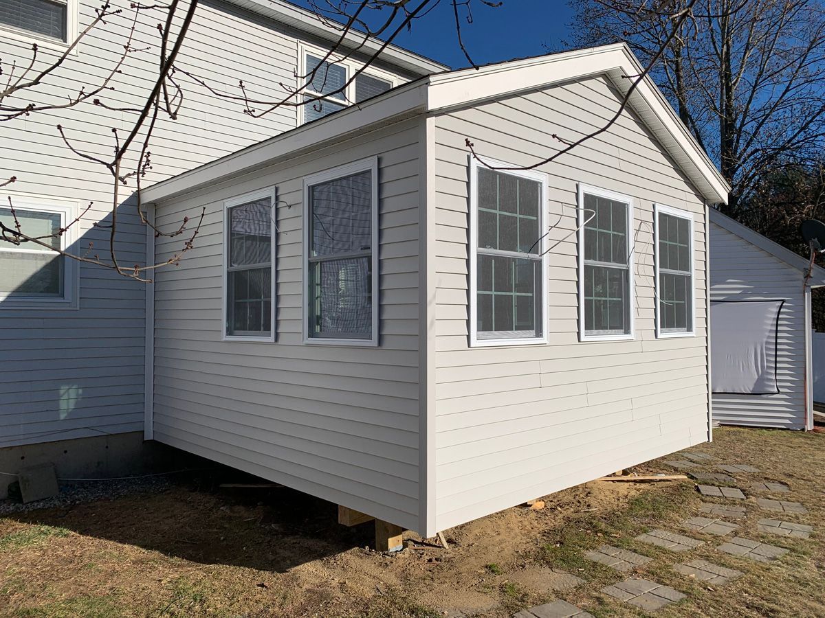 A white shed is sitting in the backyard of a house.